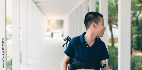 Asian special child on wheelchair is smile happily on background in Public path, Life in the education age of disabled children, Happy disabled kid concept.