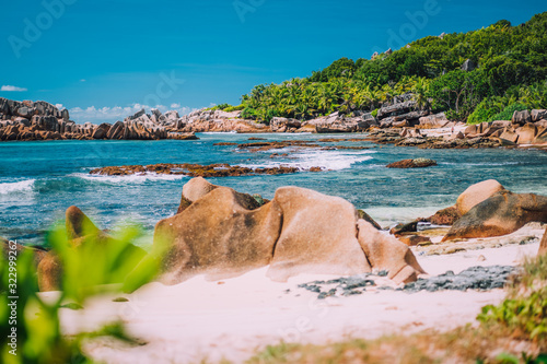 La Digue, Seychelles. Tropical exotic hidden paradise beach with granite boulders and coconut palm trees in background