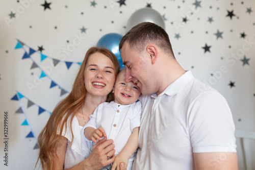 Portrait of happy mother, father and baby on the background of birthday decorationss photo