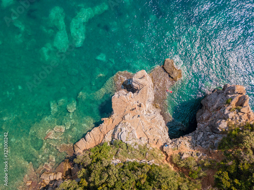 Aerial view of Mogren promontory between the Mogren beaches. Budva. Montenegro. Jagged coasts with sheer cliffs overlooking the transparent sea. Wild nature and Mediterranean maquis © Naeblys