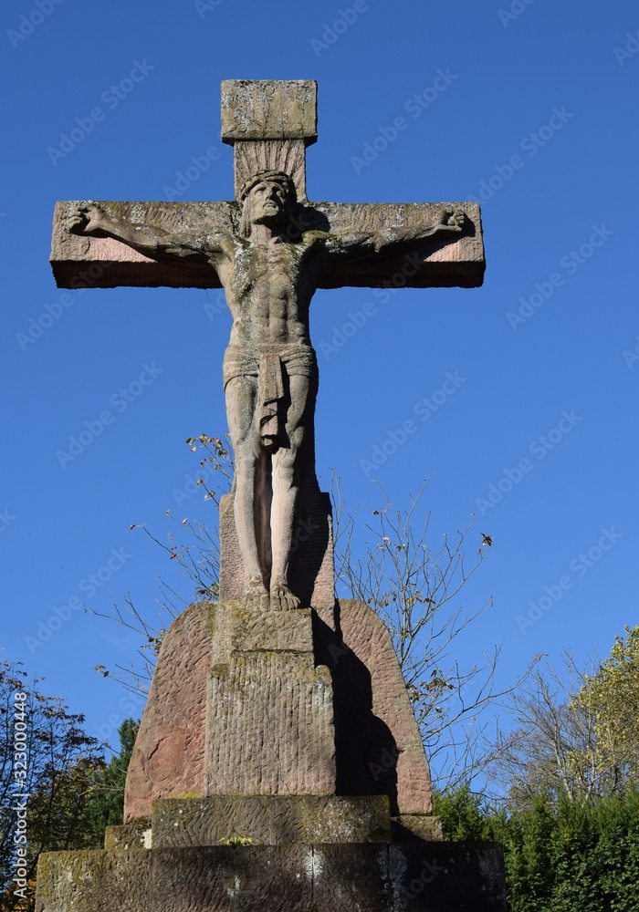 large stone cross with the body of Jesus, blue sky in the background
