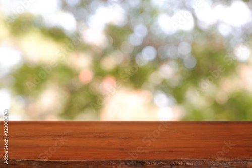 Empty wooden table in front of abstract blurred green bokeh light of garden and nature light background. For montage product display or design key visual layout - Image