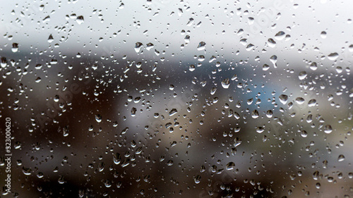 View of the city in a rainy day through a window covered with water drops © ako-photography