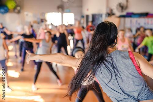 Blurred group of women in dancing aerobics class. Rear View of the trainer. Activity and healthy life style.