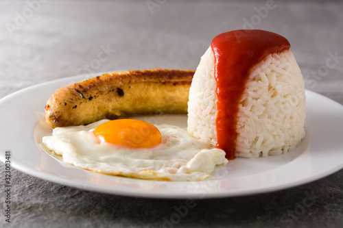 Arroz a la cubana with egg and fried banana on gray background photo