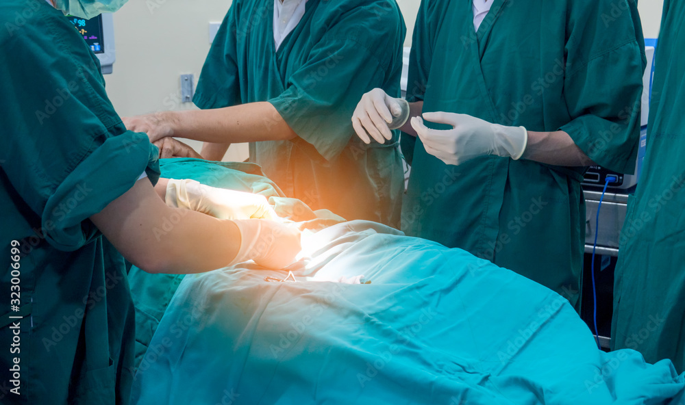 Midsection of surgery team operating Medical Team Performing Surgical Operation in Modern Operating Room or Group of surgeons in operating room with surgery equipment. Midsection of surgery team operating Medical Team Performing Surgical Operation in Modern Operating Room or Group of surgeons in operating room with surgery equipment.