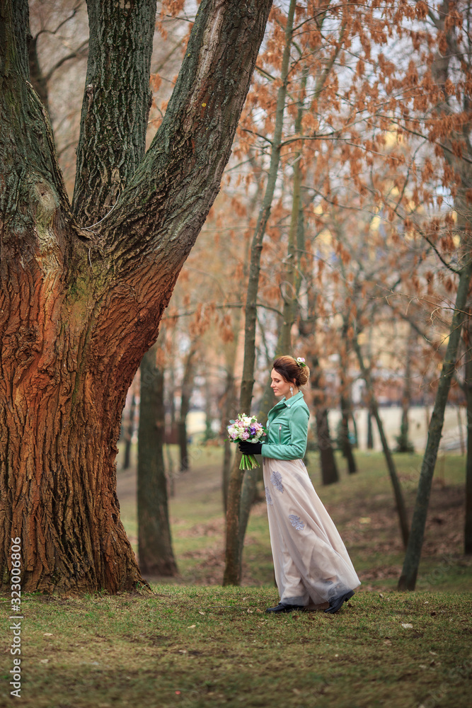 Young beautiful girl in a long dress and a green jacket and with bouquet of flowers in her hands Young beautiful girl in a long dress and a green jacket and with bouquet of flowers in her hands