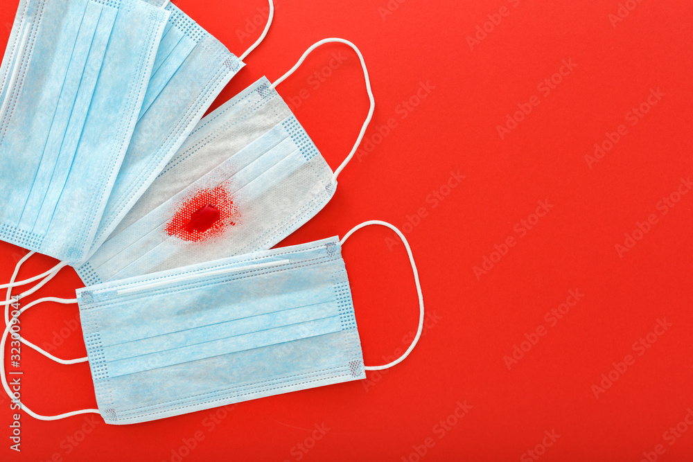Hemoptysis, coronavirus, protective surgical masks with blood on red background. Pneumonia