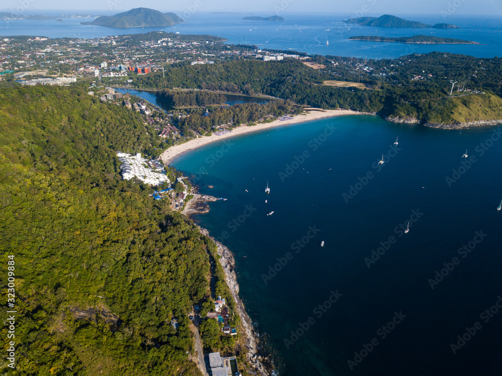beautiful aerial view of the white sand beach surrounded by green hills, yachts stand in the bay, small islands in the Adaman Sea, Nai Harn Beach, Phuket, Thailand