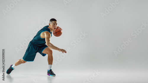Young basketball player of team wearing sportwear training, practicing in action, motion in run isolated on white background. Concept of sport, movement, energy and dynamic, healthy lifestyle. Flyer. © master1305