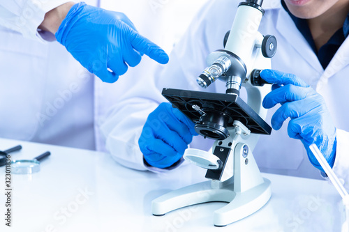 Close up Male researcher or Scientist looking through microscope in Central laboratory. Laboratory research concept.