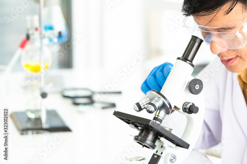 Senior Male scientist looking through a microscope in Central laboratory.