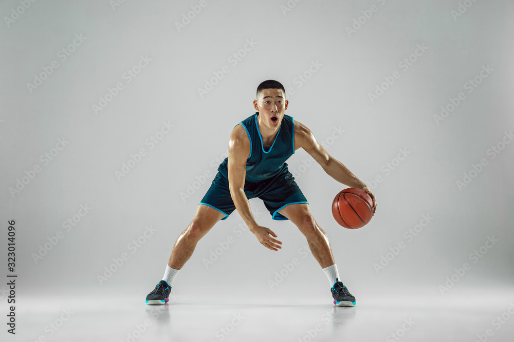 Young basketball player of team wearing sportwear training, practicing in action, motion in run isolated on white background. Concept of sport, movement, energy and dynamic, healthy lifestyle.