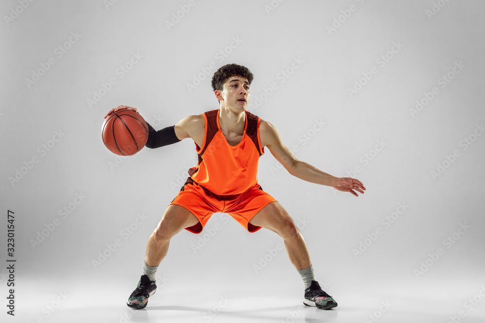 Naklejka premium Young basketball player of team wearing sportwear training, practicing in action, motion in run isolated on white background. Concept of sport, movement, energy and dynamic, healthy lifestyle.