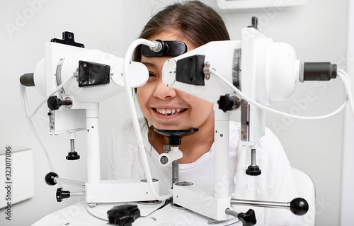 Mixed race girl near synoptophore to check her eyes. Diagnosis and treatment of strabismus in a vision clinic photo