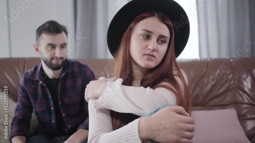 Portrait of young nervous Caucasian woman pulling back hand of husband or boyfriend calming her down. Beautiful elegant girl angry at spouse, guilty man apologizing. Lifestyle, marriage, problems. photo