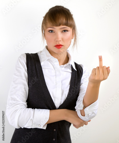 Portrait of elegant young beautiful caucasian woman in formal clothes posing over gray background. Showing middle finger doing fuck you bad expression, provocation and rude attitude photo