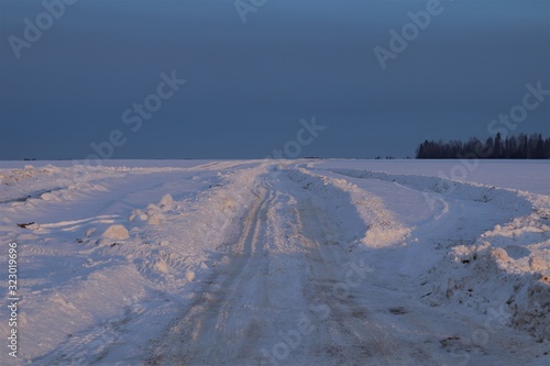 Snow field, road, blue sky, forest.