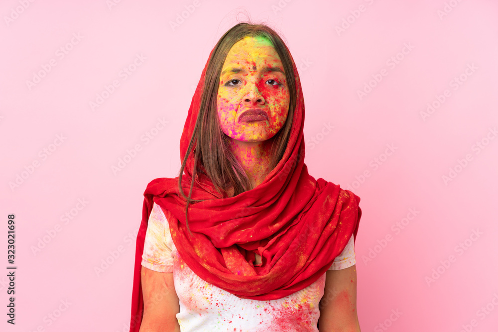 Young Indian woman with colorful holi powders on her face isolated on pink background with sad expression Young Indian woman with colorful holi powders on her face isolated on pink background with sad expression