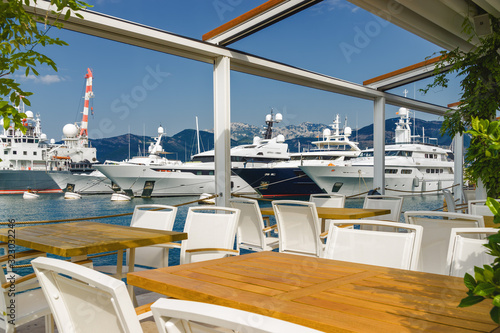 Beautiful and cozy street cafe on the background of luxury yachts at the port of Tivat, Montenegro. © Neonyn