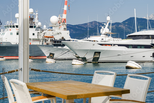 Beautiful and cozy street cafe on the background of luxury yachts at the port of Tivat, Montenegro.