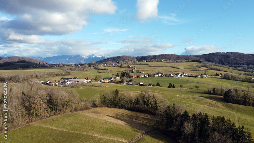 Naklejka premium Aerial view of Choisy fields, trees and mountains near Annecy, France