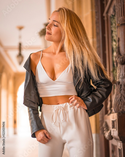 Street style, beautiful young blonde with white shirt and a jacket in the city. Looking left