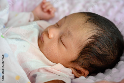 Close up new born asian baby sleep or nap on the pink blanket. Happy family and babu concept background. photo