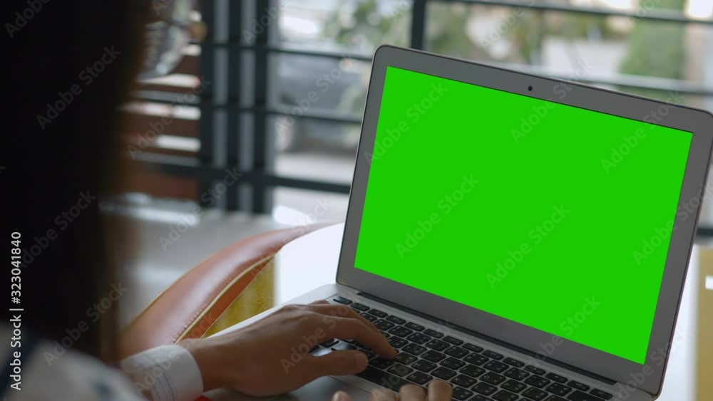 Over the shoulder shot of a business woman working looking at green screen. Office person using laptop computer with laptop green screen