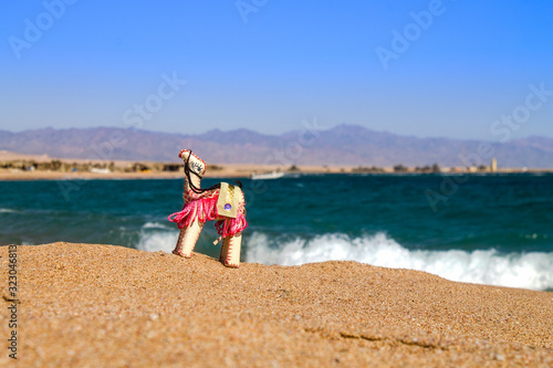 United Arab Emirates UAE Morocco Israel Egyptian souvenir camel arabic desert symbol on sand beach and sea background. Bright inanimate toy camel on the beach in the desert on the background