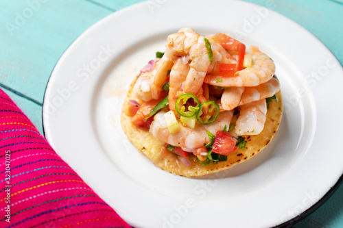 Mexican shrimp ceviche toast also called tostada on turquoise background