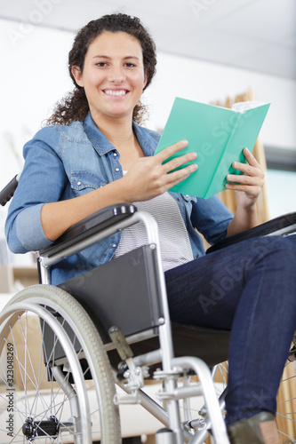 young happy woman in wheelchair reading a book