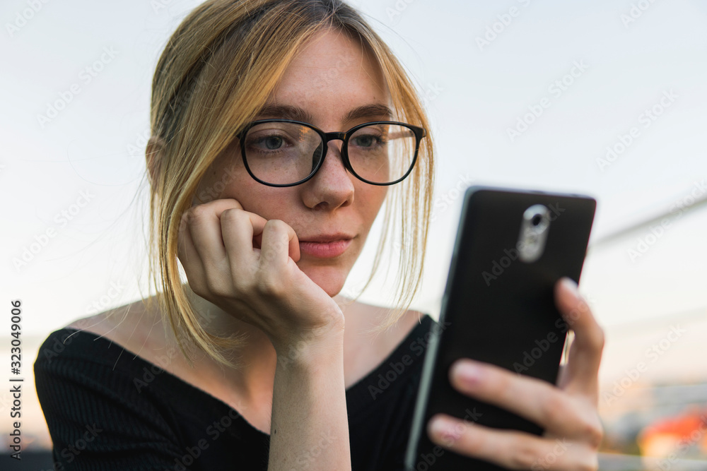 Young business woman uses phone. Good looking brunette female uses online banking on smart phone to transfer money from credit card. Girl using smart phone and chatting with business partners. Young business woman uses phone. Good looking brunette female uses online banking on smart phone to transfer money from credit card. Girl using smart phone and chatting with business partners.