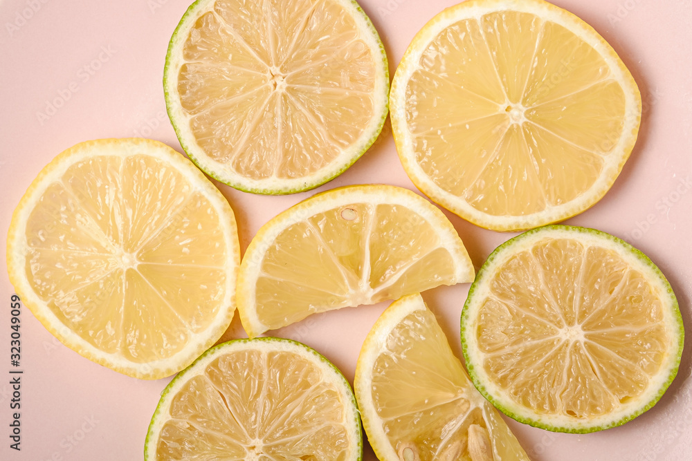 Fresh tasty lemon and lime citrus fruits slices on pink plate, minimal background isolated, top view macro