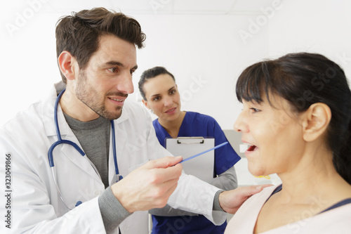 doctor checking mouth of mature female patient