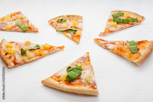 Pieces of pizza, with herbs, are located on a white background. Concept of ordering pizza at home.