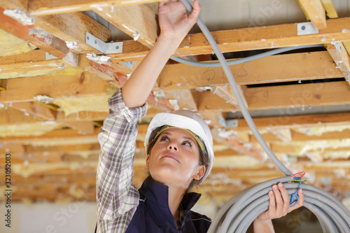 female electrician fixing ceiling lighting