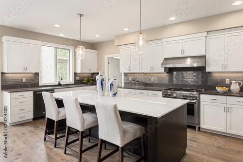 Kitchen in new home with stainless steel appliances  island  and pendant lights
