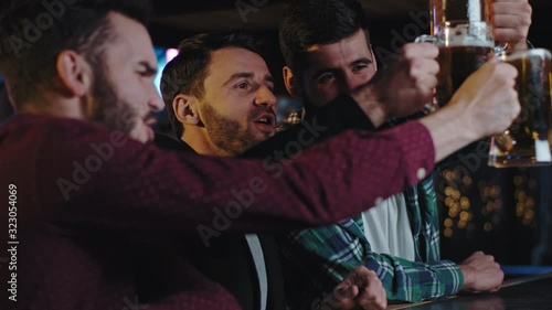 Closeup portrait in front of the camera charismatic three guys with chin in a pub drinking excited big glasses of beer and enjoying the evening time