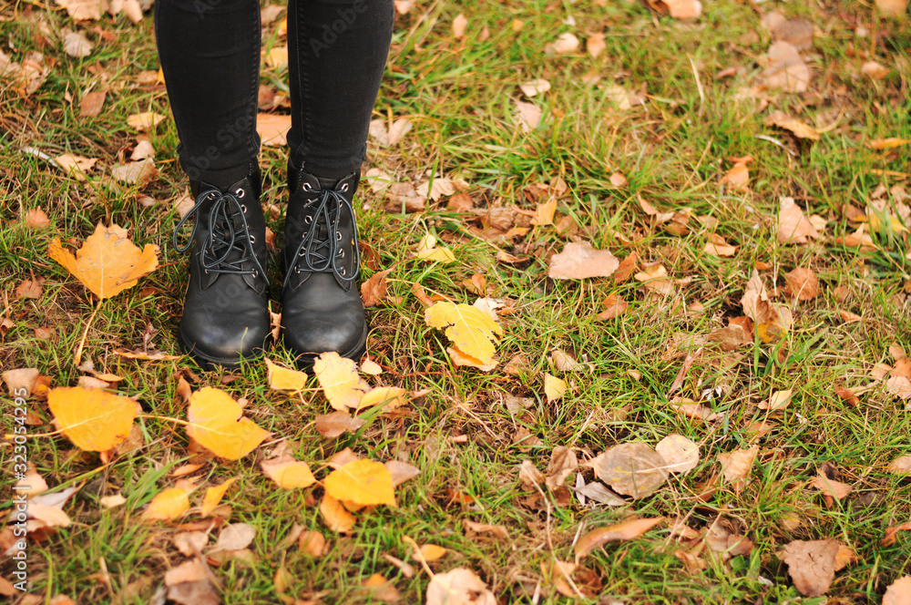 Women's black leather shoes stand on the ground covered with yellow autumn leaves. Lace up ankle boots for fall season. Women's black leather shoes stand on the ground covered with yellow autumn leaves. Lace up ankle boots for fall season.