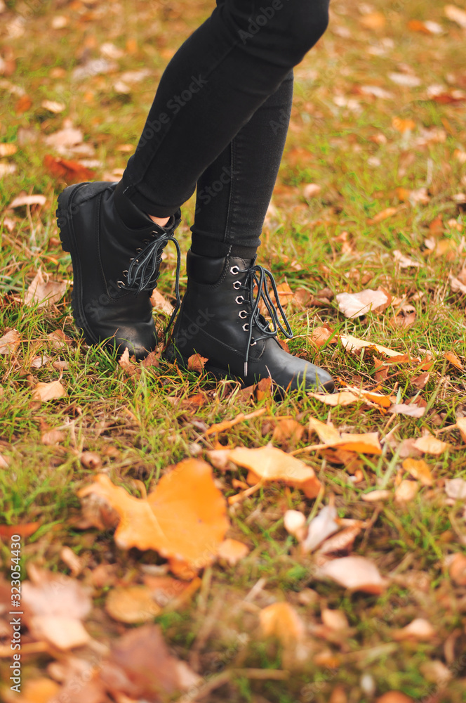 Women's black leather shoes stand on the ground covered with yellow autumn leaves. Lace up ankle boots for fall season. Women's black leather shoes stand on the ground covered with yellow autumn leaves. Lace up ankle boots for fall season.