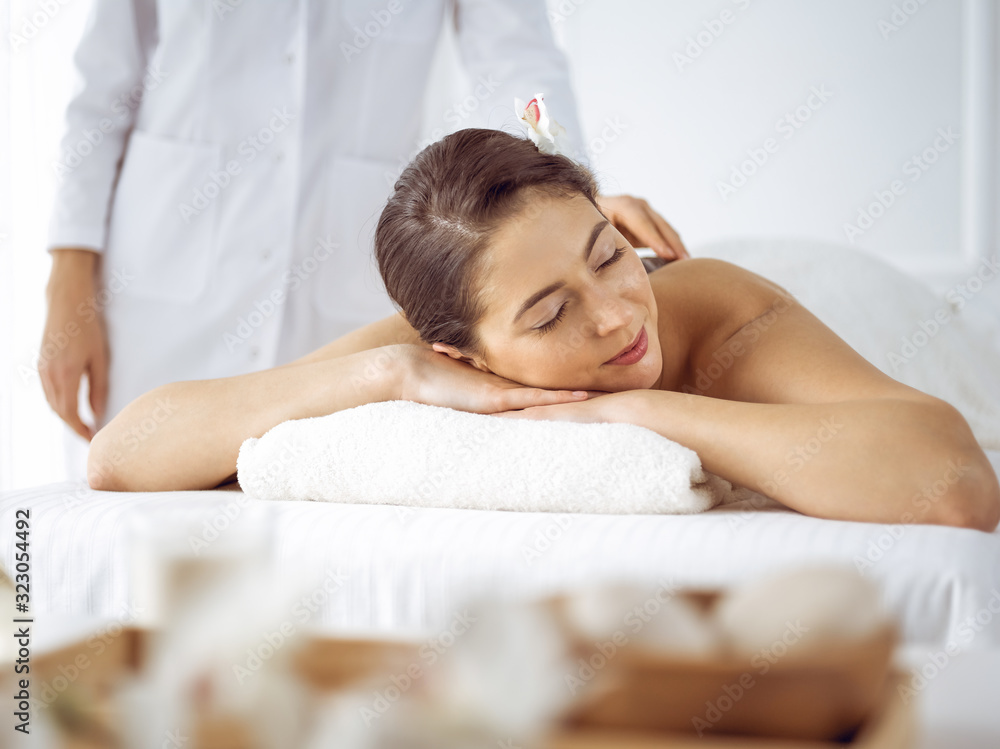 Beautiful brunette woman enjoying back massage with closed eyes. Spa and medicine concept Beautiful brunette woman enjoying back massage with closed eyes. Spa and medicine concept
