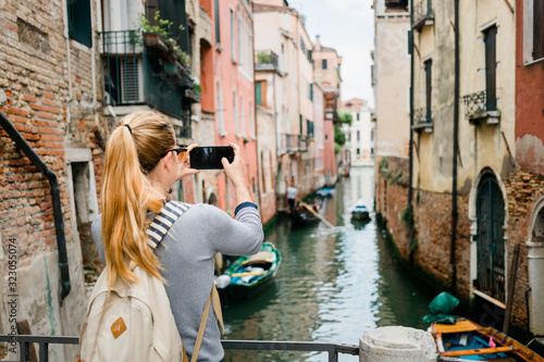 Young woman taking a photo on her smartphone of a canal in Venice, Italy © marjan4782
