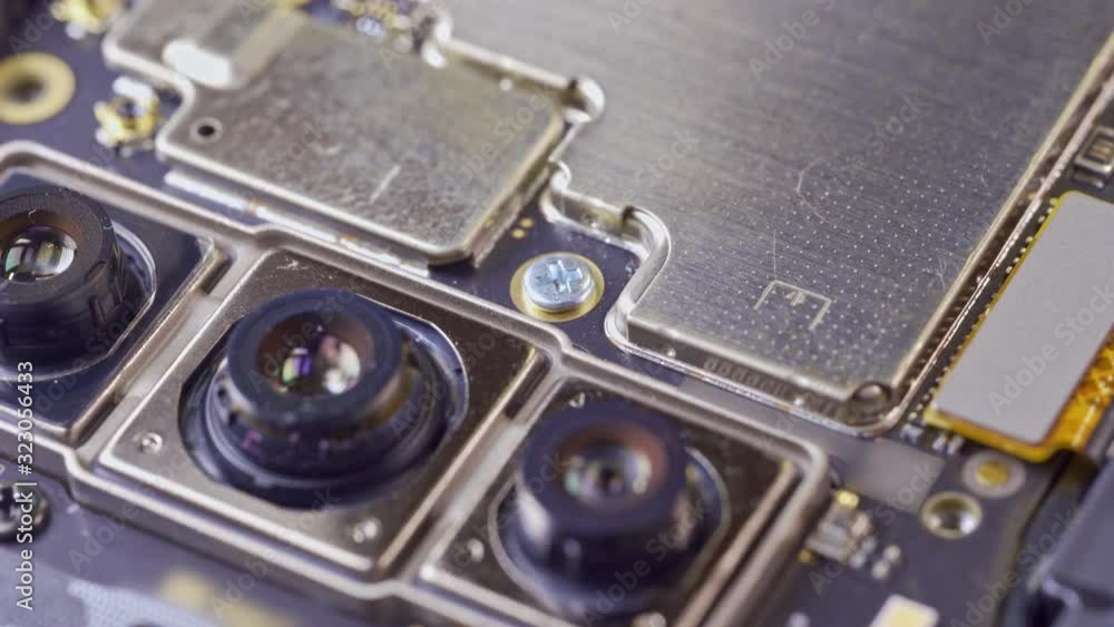 Close-up Of screwdriver Repairing Cellphone On Desk. Man repairing broken smartphone in workshop. Close-up Of screwdriver Repairing Cellphone On Desk. Man repairing broken smartphone in workshop.