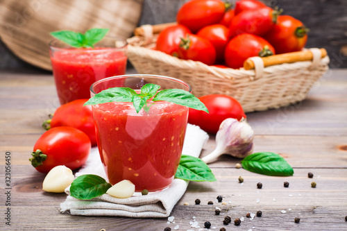 Blended fresh tomato juice with basil leaves in glasses  on a wooden table