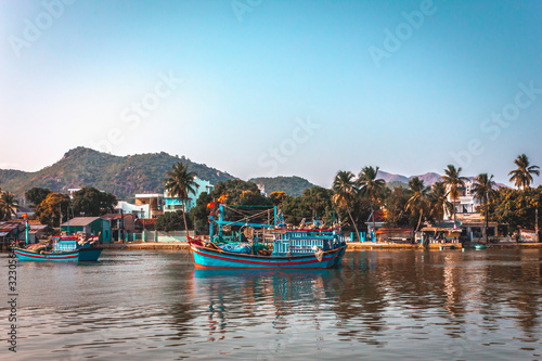 Fishing boats on the background of palm trees and buildings