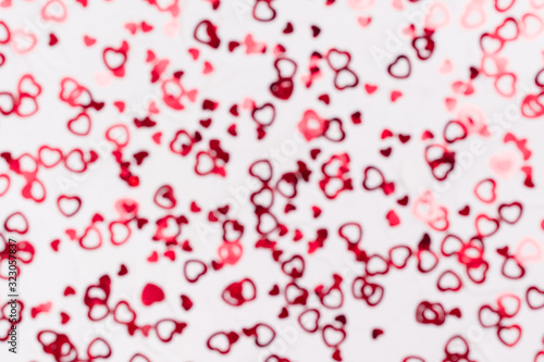 Valentine's Day. Many shiny red hearts on a white background. Defocusing. Bokeh