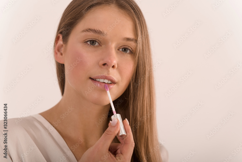 Portrait of a young beautiful woman with lip gloss in her hand. Portrait of a young beautiful woman with lip gloss in her hand.