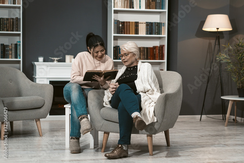 Young Woman Reads Book For Her Elderly Mother
