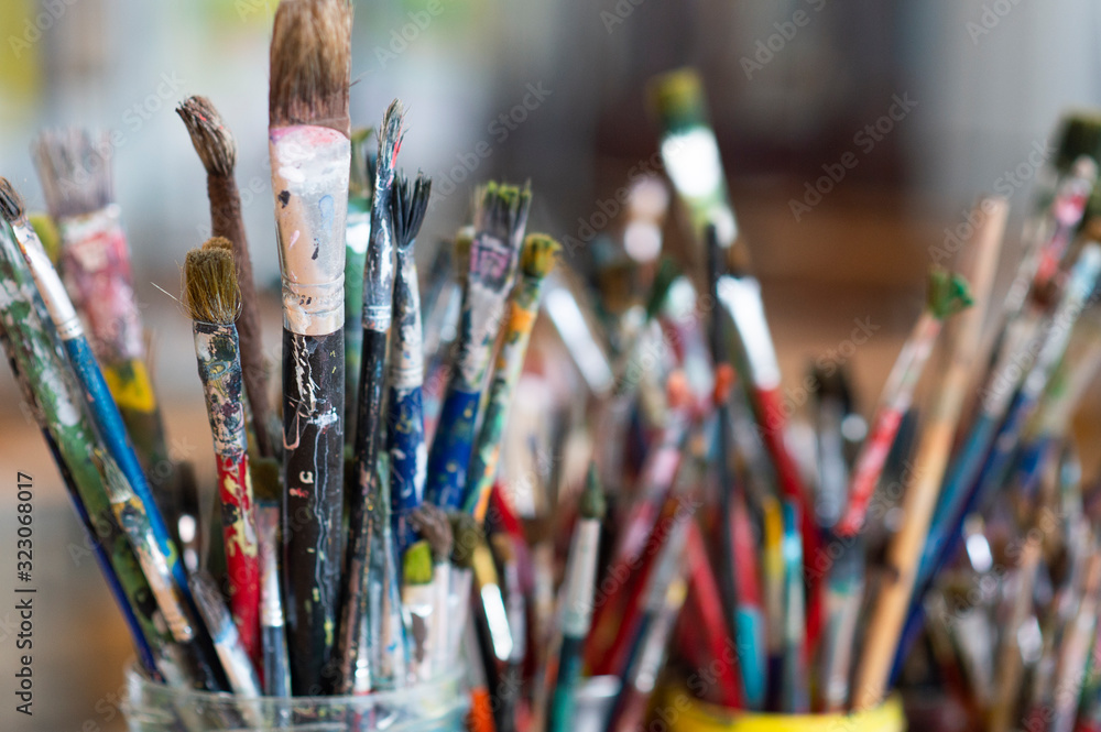 Fototapeta premium A lot dirty artist paint brushes in a bucket